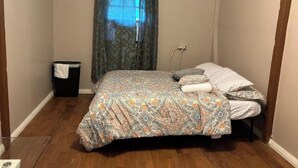 A small, single-bed room with a patterned bedspread, a bedside table, and a trash bin. - Modern and Centrally located. (Forte de France)