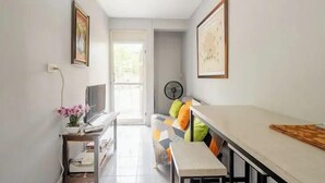 A narrow hallway with a desk, a chair, a fan, and a door leading to a bright room. - Camperdown Place (Kingston)