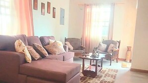 Un salón amplio con un sofá grande, una mesa de centro y un ventilador de techo.