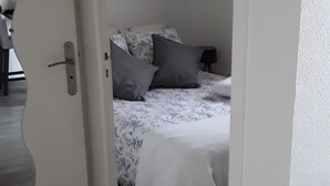 Ein Schlafzimmer mit Bett, Kissen, einem Nachttisch und einem kleinen Fenster.