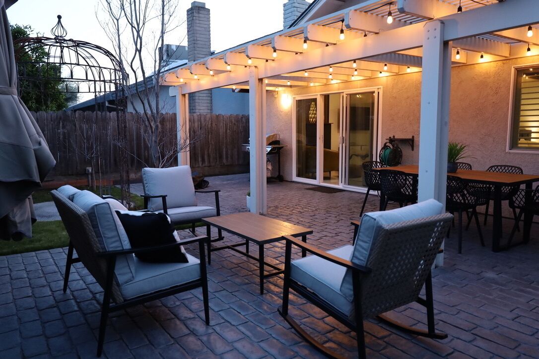 An outdoor patio area with a covered seating area, a table, and a grill.