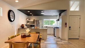 Una cocina moderna con una isla central, mesa de comedor de madera y sillas.
