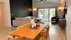 Una sala moderna con una mesa de comedor de madera, sillas amarillas, un sofá y una pared de acento negra.