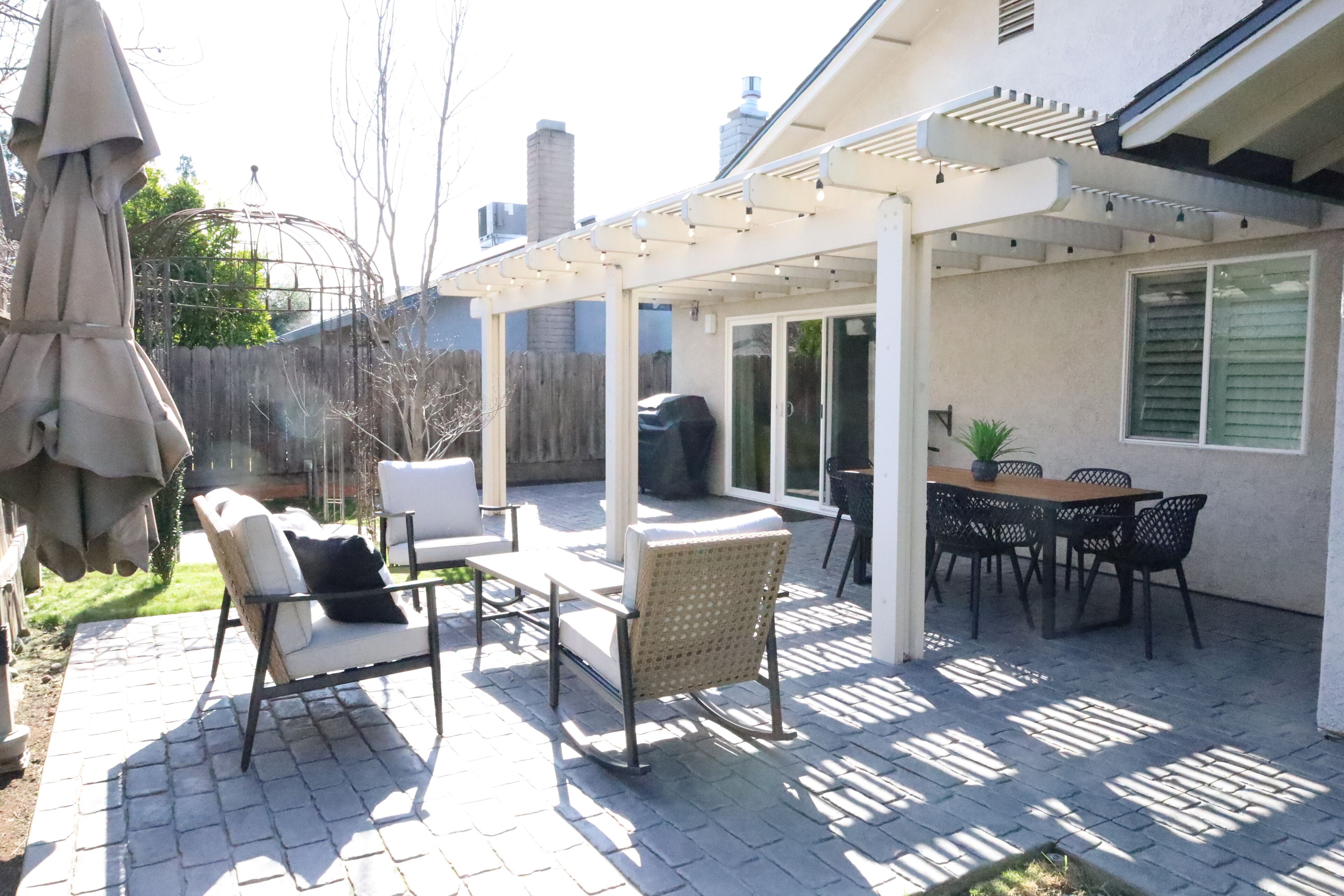 Een terras met tuinmeubilair, een pergola en een eethoek.