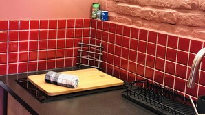 Une cuisine avec des carreaux rouges, un plan de travail en bois, un évier et une planche à découper.