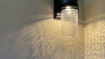 A wall-mounted light fixture with a textured glass cover and a switch below it.