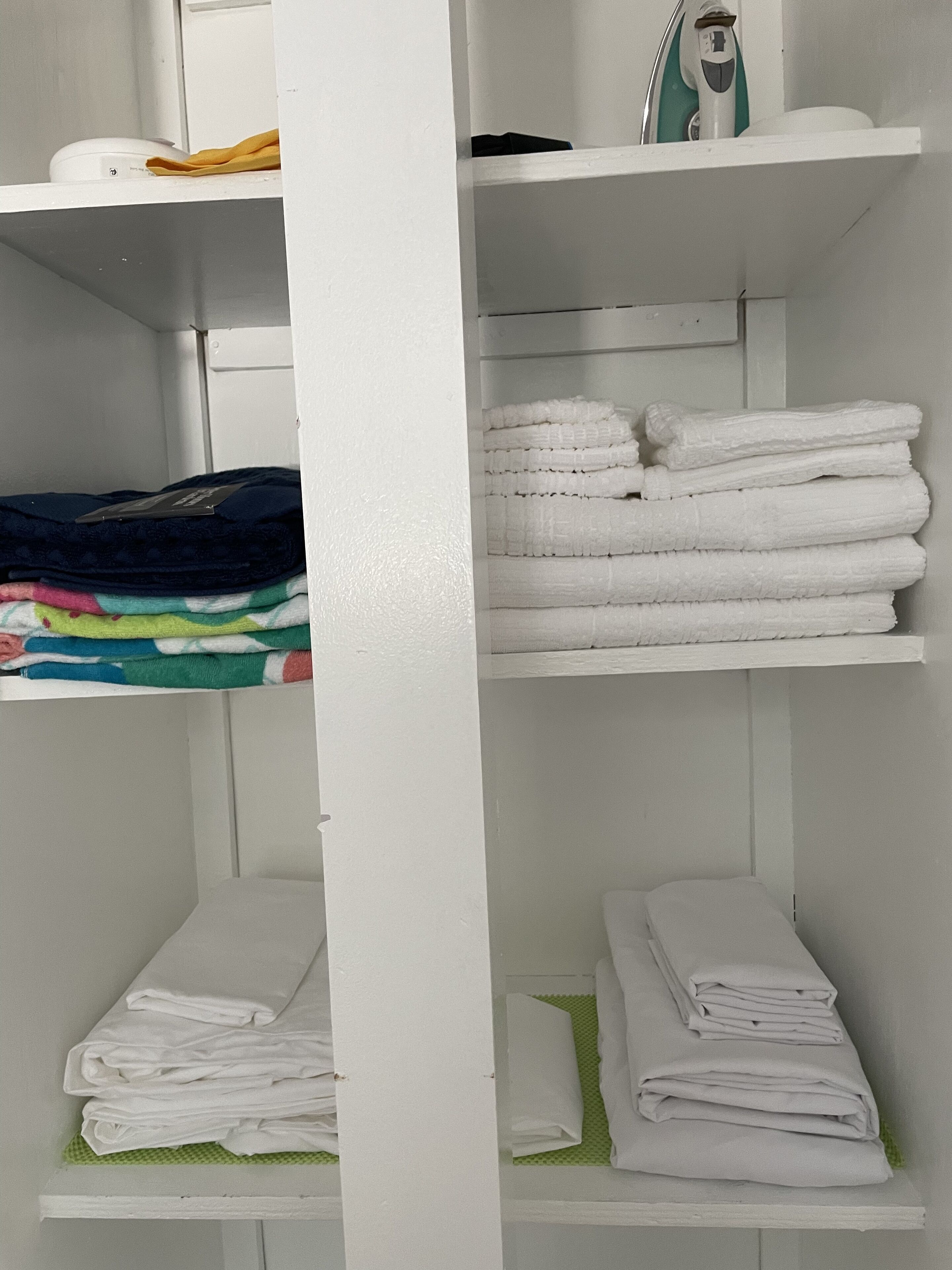 Een witte rek met opgevouwen handdoeken en een haardroger.