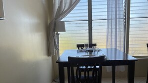 Un comedor con una mesa y sillas, un florero en el suelo y vistas al exterior.