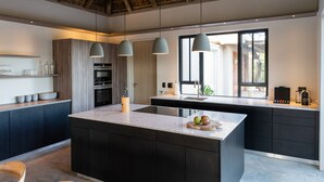 A modern kitchen with a large island, pendant lights, and a view to the outside.