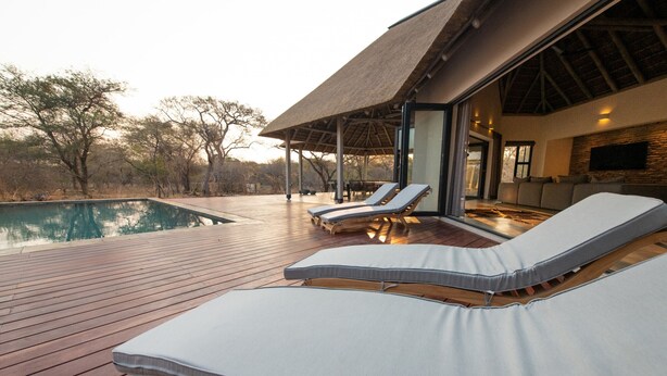 A poolside area with lounge chairs and a covered seating area. - Villa Appelblaar: luxury 4 bedroom villa home in the South African bush (Hoedspruit)