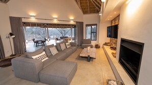 A spacious living area with a large gray sectional sofa, a coffee table, and a fireplace. - Villa Appelblaar: luxury 4 bedroom villa home in the South African bush (Hoedspruit)