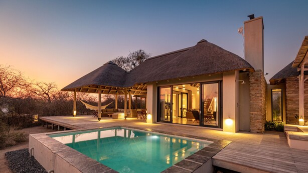 A modern villa with a swimming pool, outdoor seating, and a covered patio.