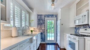 Una cocina moderna con armarios blancos, microondas integrado y estufa.