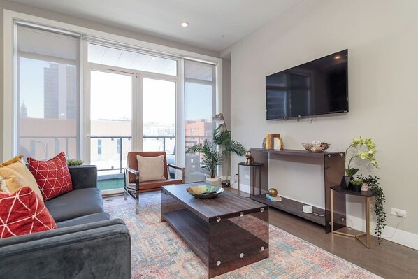 A modern living room with a sofa, coffee table, and TV. - 2 Newly Built Luxury Condos with Private Roofdeck! (Chicago)