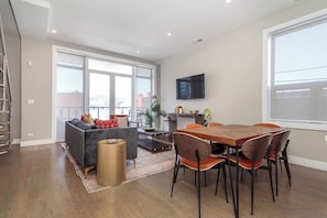 A modern living room with a sofa, coffee table, and dining table with chairs. - 2 Newly Built Luxury Condos with Private Roofdeck! (Chicago)