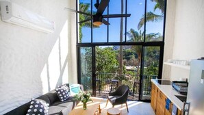 A modern living area with a sofa, chairs, a wooden table, and a balcony with a view of palm trees. - Tranquility at La Isla Brisas 2 (Sayulita)