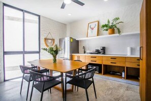 Una cocina moderna con comedor, que incluye una mesa y sillas de madera, un refrigerador y una cafetera.