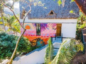 Una casa con techo de paja y un mural colorido en la pared.