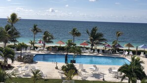 A pool area with lounge chairs and umbrellas, a clear view of the ocean, and a no swimming sign.