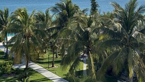A resort with a pathway leading to the beach, surrounded by palm trees and a view of the ocean.