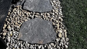 A stone pathway with steps leading to a grassy area.