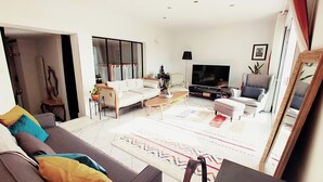 A living room with a sofa, armchairs, a coffee table, a TV, and a large mirror. - 靠近巴黎戴高乐机场，国际展览中心，法国体育场，迪斯尼乐园，花园365平面，200平面别墅，可容纳14个人，五间卧室，三个浴室，花园可烤肉，大餐桌和阳伞，三个秋千 (Aulnay-sous-Bois)