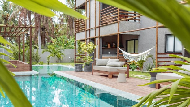 A swimming pool with a hammock, a sofa, and potted plants. - Apartamento 02 Quartos - São Miguel dos Milagres (São Miguel dos Milagres)