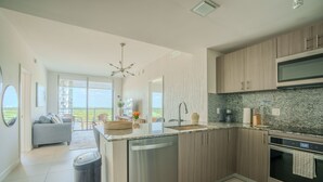 A modern kitchen with a dishwasher, oven, and granite countertop. - Stylish 2BR Condo. Walk to Restaurants & Shops (Doral)