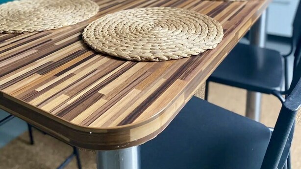 A wooden dining table with woven placemats and black chairs. - Appartement (Damery)