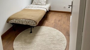 A bedroom with a bed, a round rug, a hanging light fixture, and a skylight. - Appartement (Damery)
