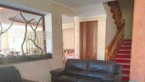 Una sala de estar con un conjunto de sofá, una ventana con vistas y una escalera.