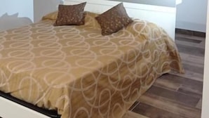Un dormitorio con techo de madera, una cama con ropa de cama estampada y un cabecero blanco.