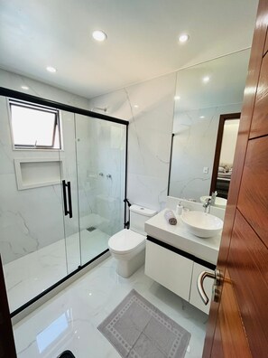 A modern bathroom with a glass shower enclosure, a toilet, a sink, and a vanity.