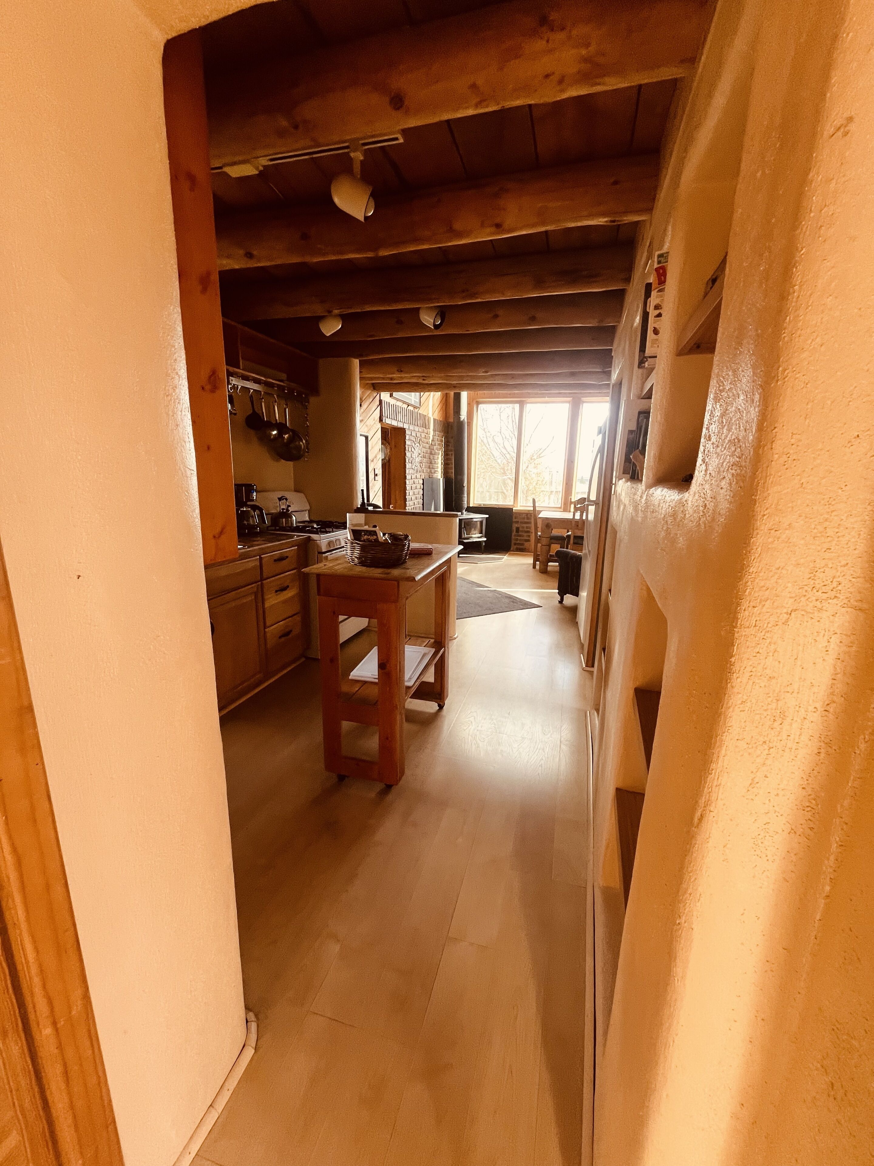 A wooden interior with a kitchen area, including a stove, sink, and hanging pots.