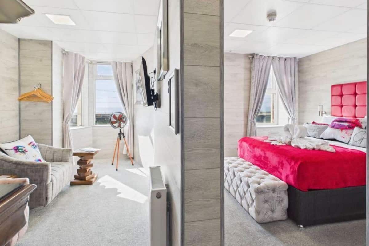 A modern hotel room with a bed, a desk, a chair, and a window.