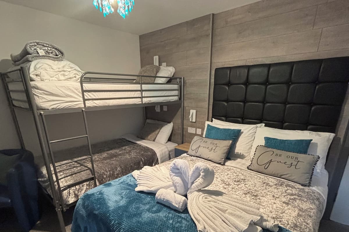 A bunk bed with a headboard, a blue blanket, and a towel arrangement.