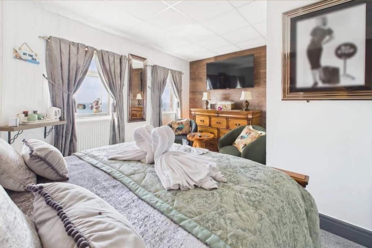 A hotel room with a bed, a dresser, a television, and a framed picture on the wall.