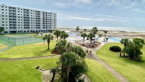 Un hotel con campo da tennis, area piscina e vista sulla spiaggia.