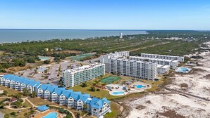 Un hotel sulla costa con diversi edifici, una spiaggia e una vista limpida sull'oceano.