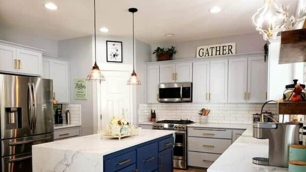 A modern kitchen with white cabinets, a marble island, and a 'GATHER' sign on the wall. - Beautiful Modern Farmhouse
 (Keizer)