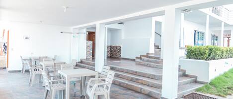 Un amplio espacio al aire libre con un patio, varias mesas y sillas, y una escalera que lleva a un nivel superior.