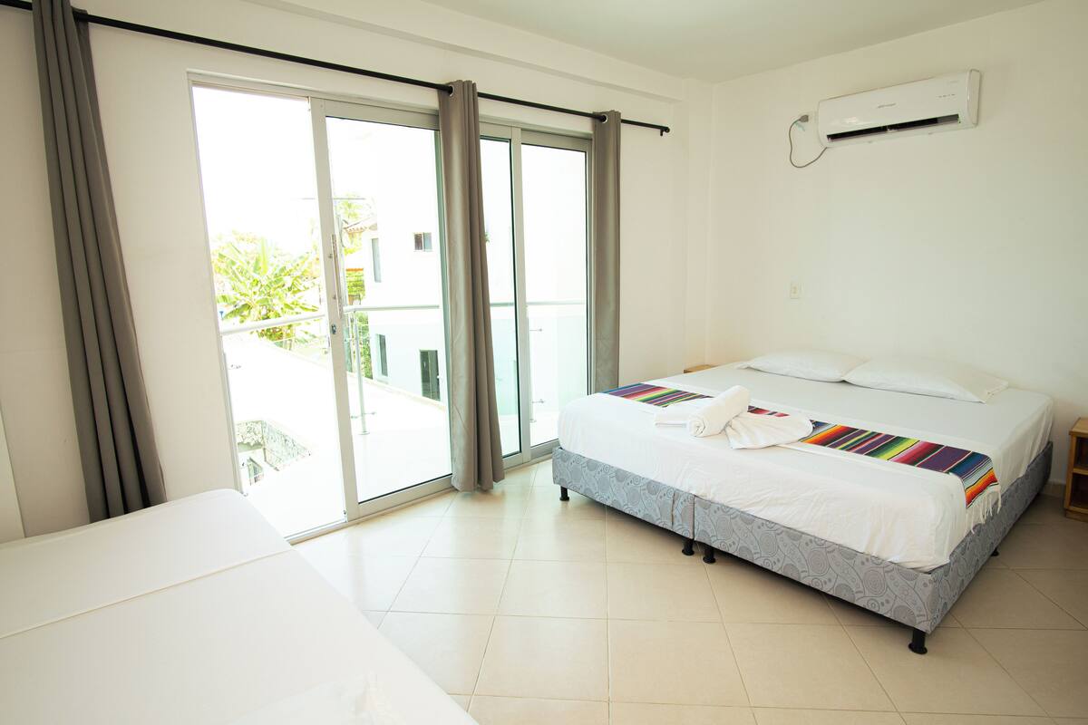 Une chambre d’hôtel avec un lit, une fenêtre avec des rideaux, une porte coulissante et un appareil de climatisation.