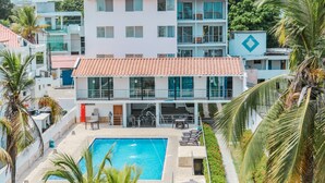 Un hotel moderno con piscina, varios balcones y vistas de edificios circundantes.