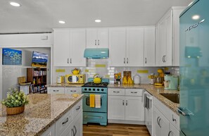 A kitchen with white cabinets, a blue stove, and a teal refrigerator. - Downtown Quartet - 4 Bungalows w/Fenced Yards, AC, W/D, Smart TVs, & Speedy WiFi (Flagstaff)