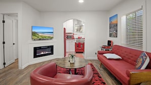 Ein Wohnzimmer mit Kamin, einem roten Sofa und einem an der Wand befestigten Fernseher.