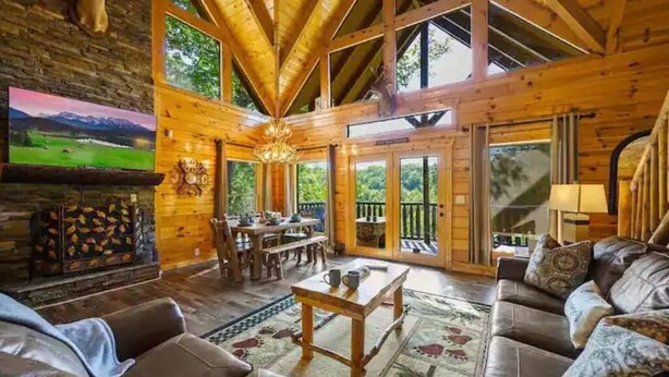 A spacious wooden interior with a high ceiling, a fireplace, a dining area, and a balcony. - 8 King Beds, 3 Levels, Hot tub, Pool table, Bar, Wood Soaker, Vaulted with VIEWS (Gatlinburg)