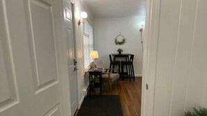 A hallway with a wooden floor leading to a dining area with a table and chairs.