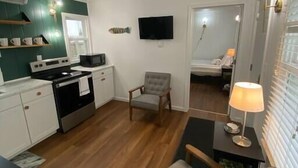 A compact living space with a kitchenette, a dining area, and a seating area with a lamp.