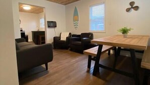 Een woonkamer met een houten plafond, een eettafel en een bank.