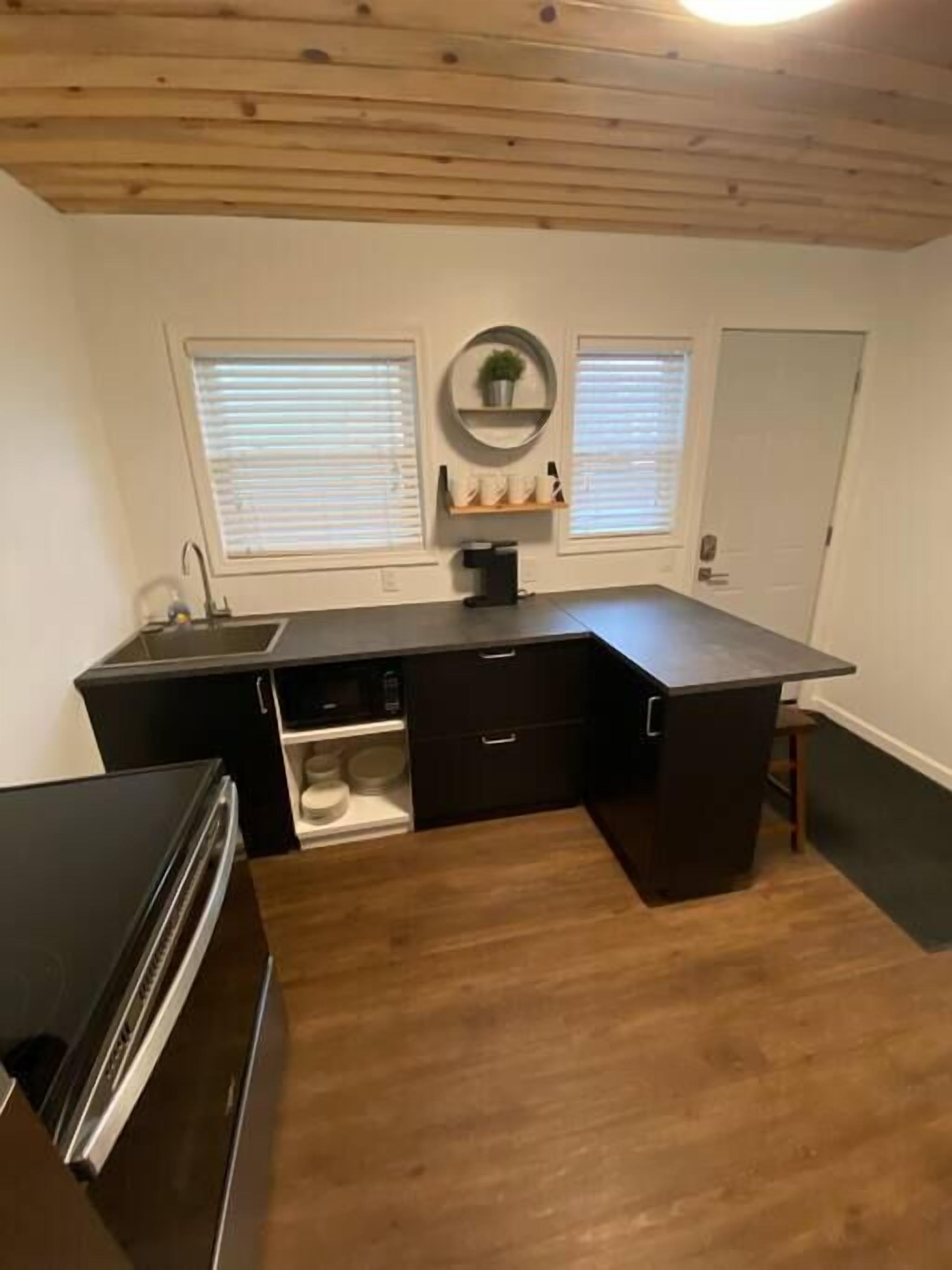 A compact kitchen with a dark countertop, wooden cabinets, and a built-in sink.